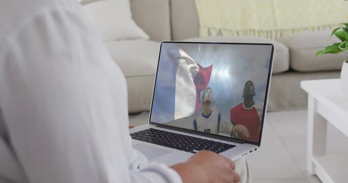 Mature woman holding laptop on lap watching athletes shifting solo to pair cheering at waving flag