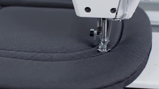 Close-Up View Of A Sewing Machine Stitching Black Fabric In A Professional Textile Manufacturing Setting