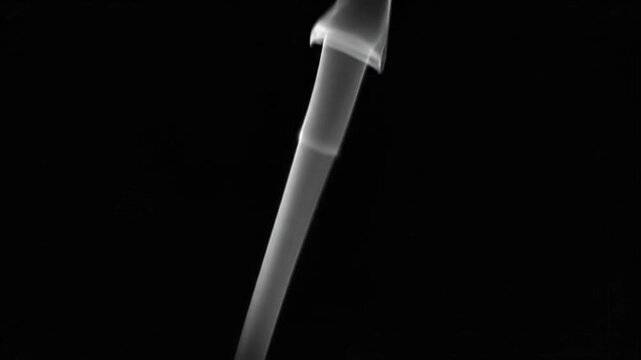 Thin white smoke rising on a black background, creating an abstract and ethereal visual effect with soft movement.