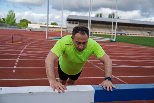 Man exercising doing push-ups on hurdle at track