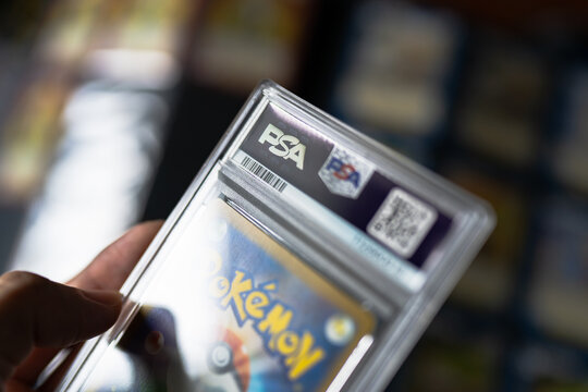 Bangkok, Thailand &ndash; July 15, 2026: Close-Up of a Collector Holding a Rare Graded Pok&eacute;mon Trading Card in a Protective Plastic Display Case.