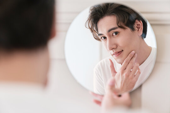 Closeup portrait of handsome beautiful asian boy mirror makeup routine with copy space. Beauty influencer guy with perfect glow skin dress up. Healthcare man lifestyle cosmetic blogger hair concept