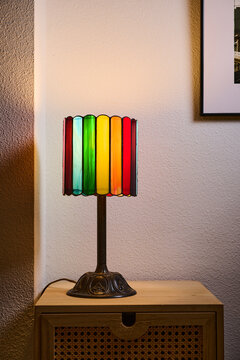 Close-up of a small, multicolored table lamp resting on a piece of living room furniture.