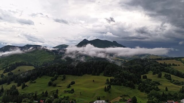 Aerial Hyperlapse Mountain Village With Dramatic Clouds and Fog Over Rocky Peaks