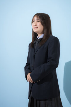 水色背景で制服で立つ見上げる笑顔の女子中学生や高校生のイメージ