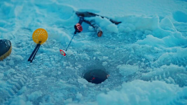 An Ice Fishing Rod Is Positioned Through An Ice Hole On A Frozen Lake During The Winter Season. Close-up Shot