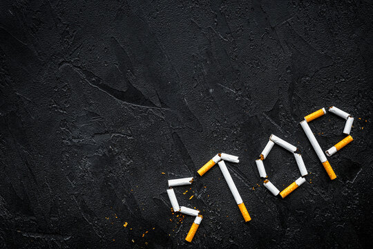 Stop smoking. Word stop lined cigarettes on black background top view copy space