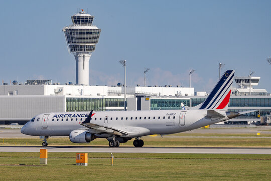 Ein Embraer 190 der Air France (Kennung F-HBLC) rollt auf dem Vorfeld des Flughafens M&uuml;nchen. Im Hintergrund ist der Kontrollturm des Franz-Josef-Strau&szlig;-Flughafens.