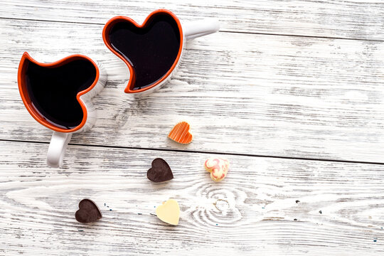 Dating on Valentine's day concept. Heart-shaped mugs and sweets on white wooden background top view copy space