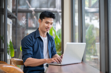 Young Asian freelancer man working on laptop at modern cafe workspace © bongkarn