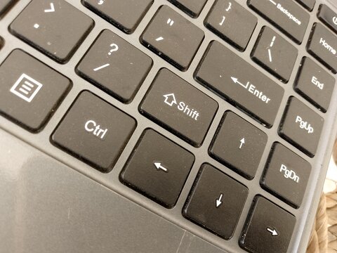 Close up overhead view of a dark grey computer keyboard showing the shift ctrl enter and arrow keys in a high contrast studio setting perfect for professional technology with individual keys with work