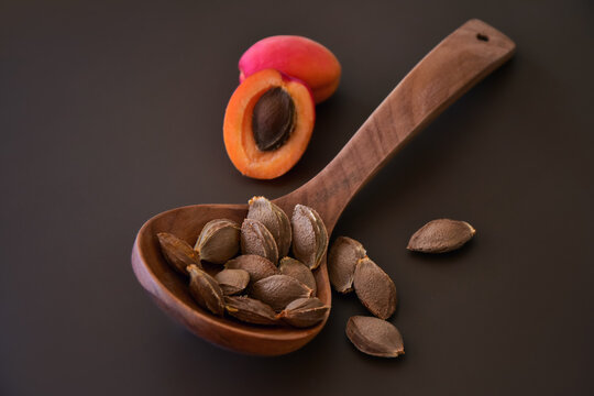 Sliced open apricot by a wooden ladle with kernels