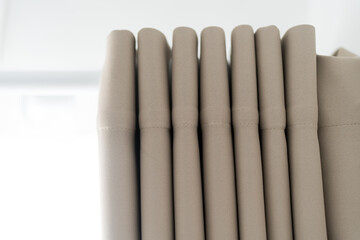 Close up of a brown fabric curtain on a hidden metal rod under a white ceiling © Dontree
