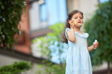 Fototapeta premium Little girl blowing soap bubbles in summer park