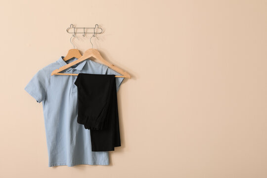 Light blue polo shirt and black trousers on wooden hangers, school uniform concept, ready for the new academic year