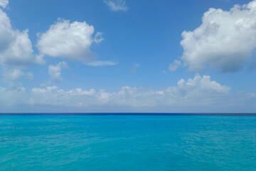 Scenic view of the open Caribbean sea with vibrant turquoise water under a bright blue sky with white fluffy clouds.  Background for travel concepts, summer vacations, and resort themes © Alexander