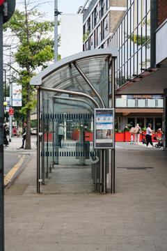 Corby, Northamptonshire, United Kingdom - July 15, 2026: Modern glass bus shelter on city street in urban business district