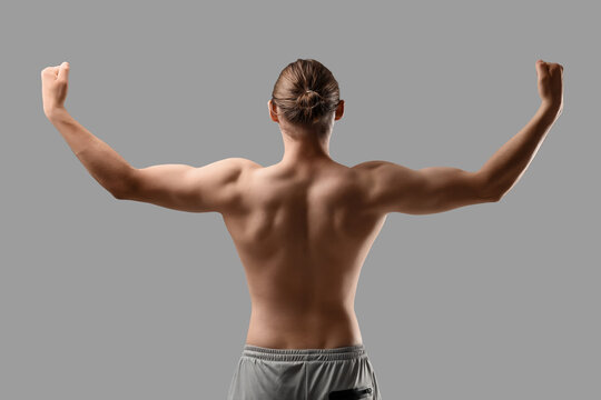 Sporty muscular man on grey background, back view