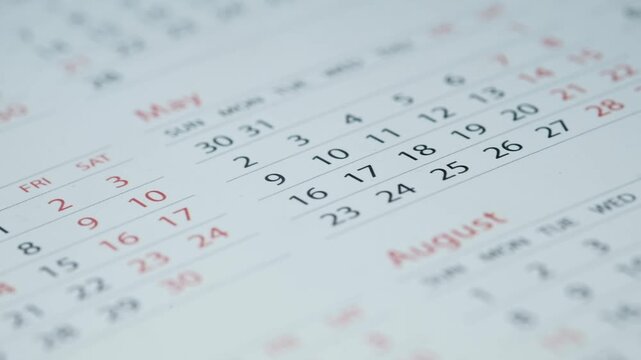 Close up video footage of turning pages of calendar showing dates and months