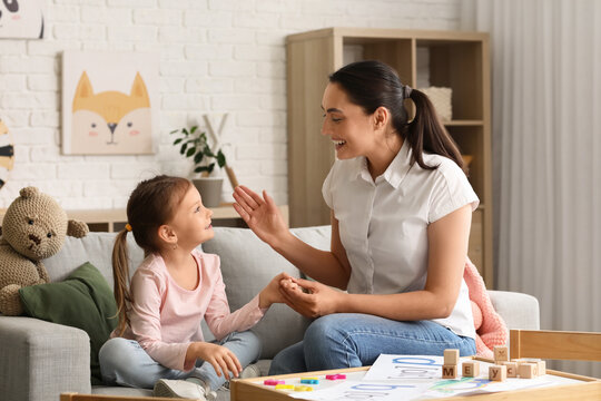 Female speech therapist working with little girl in office