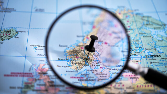 Close-up of a printed map with a magnifying glass highlighting Oslo