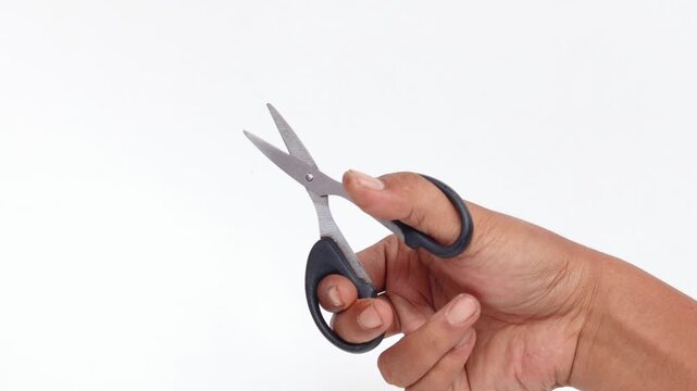 Close-up of an Asian man's hand making a cutting motion with a pair of scissors isolated on a white background.