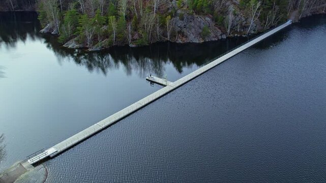 Long wooden floating bridge crossing the calm waters of Stora Delsj&ouml;n lake in Gothenburg, Sweden. The footage highlights the serene nature and scenic outdoor surroundings.