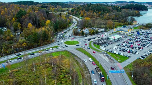 Rush hour near Vikingagrillen fast food restaurant and Jordfallsbron bridge, connecting E45 and E6. This aerial drone view shows traffic congestion at a roundabout in Sweden during peak travel time.