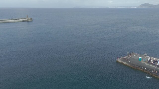 Drone flying backwards from castro urdiales pier over bay of biscay