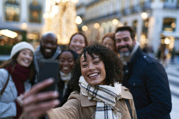 Obraz premium A joyful group of friends captures a selfie in an outdoor setting adorned with festive lights, conveying a sense of camaraderie, joy, and shared memories.
