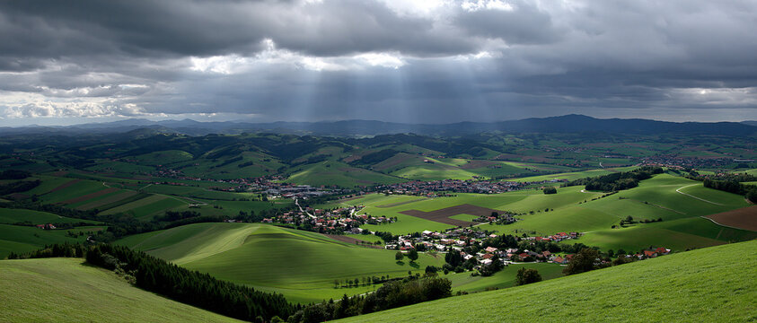View of rolling hills and town under cloudy sky