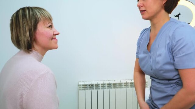 Professional cosmetologist engages in consultation with client in modern spa clinic. Beautician with focused expression discussing skin care options or cosmetic procedures. Concept of beauty services.