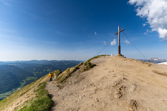 Hiker walking towards the Fellhorn summit cross in Allgaeu Alps