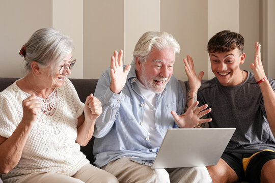 Three generations of family. A senior woman. A senior man. And a young man. Sitting on a sofa and celebrating a surprising achievement