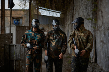Fototapeta premium An armed group of three people practice with weapons on a training field outdoor