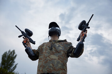 Fototapeta premium Well-armed and clothed soldier, holding one military gun in each hand, bottom view