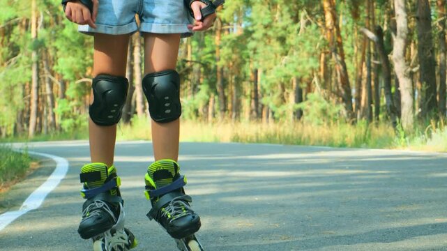 Carefree positive adorable girl roller skating in public park. Joyful child having fun, enjoying rollerblading outdoors on summer day