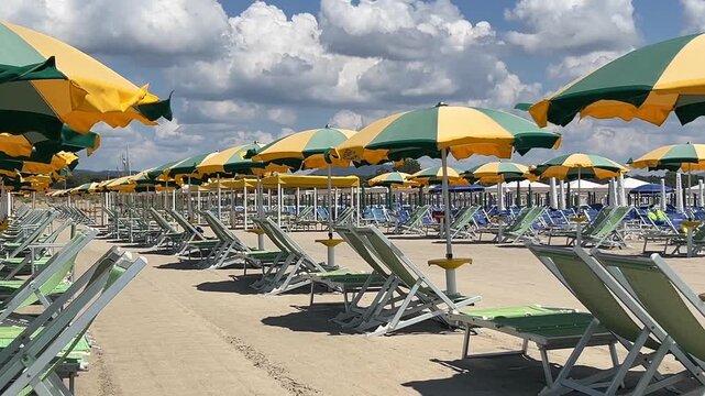Beach with rows of colorful umbrellas and sunbeds on traditional beach Tuscany Italy. 