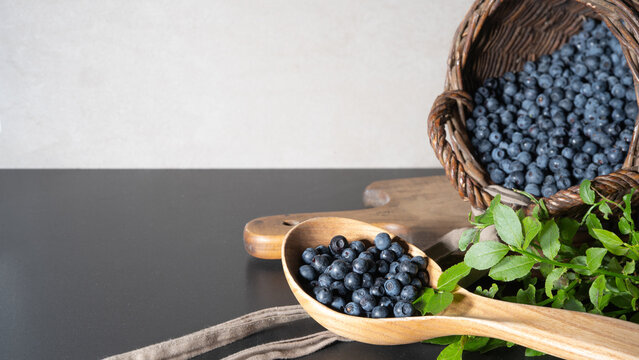 Top view from fresh Vaccinium myrtillus, wild blueberry blueberries and green leaves in a basket on a table