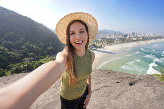 Holidays in Brazil. Young tourist woman takes selfie from lookout in the city of Guaruja, Sao Paulo, Brazil.
