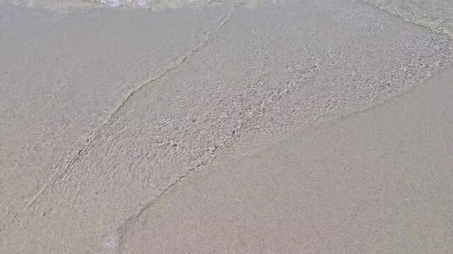 Sea wave washing away heart shape drawn in wet beach sand along shoreline. Love fading, broken relationship, impermanence, memories, romance and changing emotions concept.