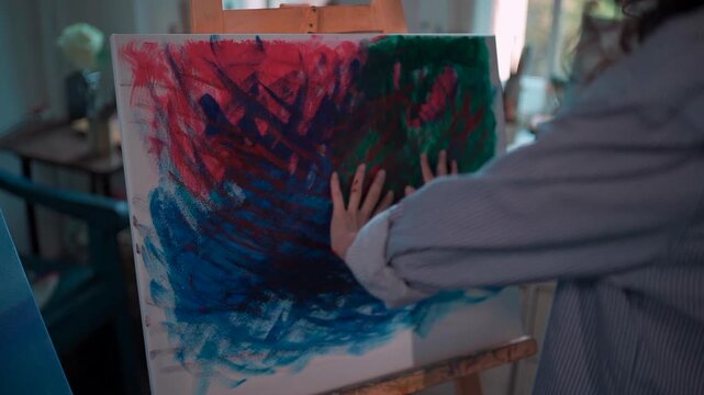 Paint covered artist hands creating abstract canvas in creative studio with expressive acrylic colors, Female painter showing colorful palms during artistic process with contemporary artwork 4k