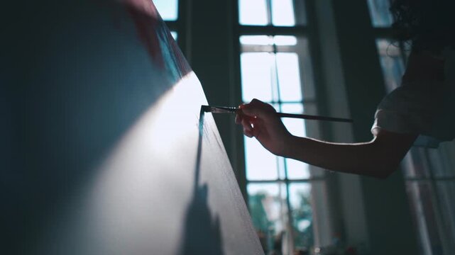 Female artist painting canvas with brush in sunlit creative studio and dramatic window shadows, Silhouette painter creating contemporary artwork on easel with natural daylight and artistic process 4k