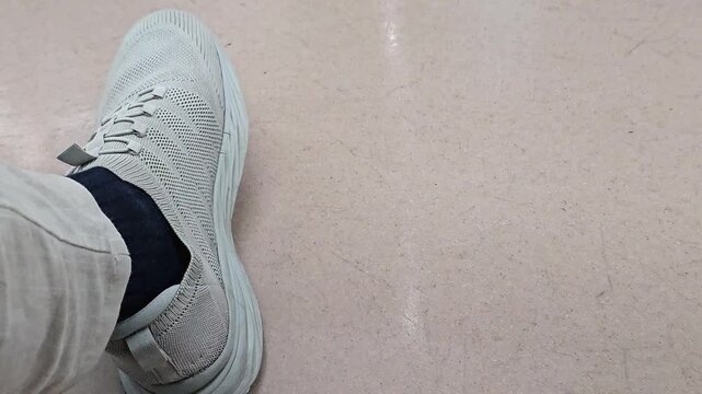 Close up of person repeatedly tapping foot on floor while sitting indoors. Restless leg movement footage showing impatience, waiting, nervous habit, anxiety, stress or boredom concept