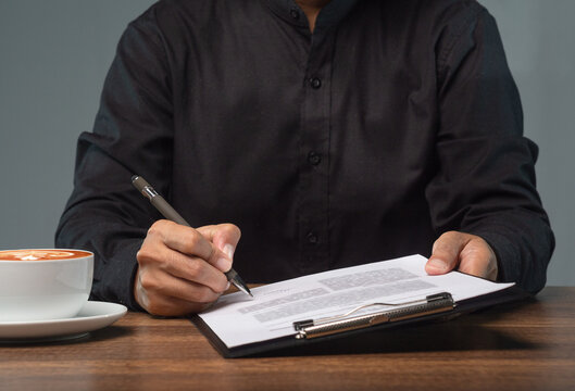 Businessperson Signing Documents on Clipboard