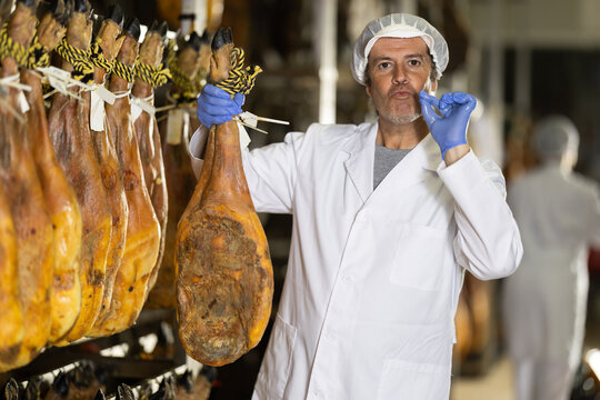 Satisfied male worker at jamon factory shows off the finished jamon