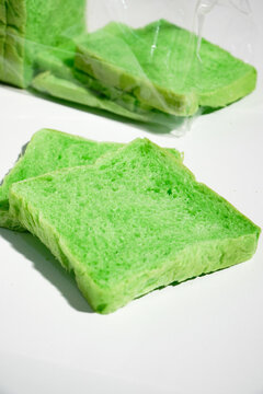 Green pandan bread loaf slice on a white background. Sliced, stale bread with a moldy coating on a wooden plate. Breakfast Concept 