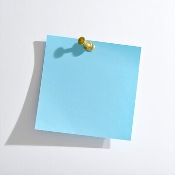 A single, blank, light blue square note is pinned to a white surface
