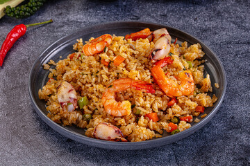 Fototapeta premium Seafood fried rice with shrimp and squid on dark plate