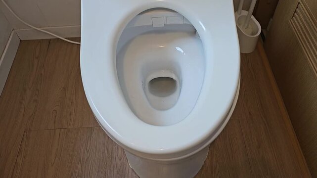 Automatic smart toilet lid opens when person approaches in modern bathroom. Motion sensor activated Japanese style intelligent toilet demonstrating touchless hygiene, home automation